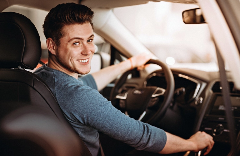 uśmiechnięta mężczyzna za&nbsp;kierownicą